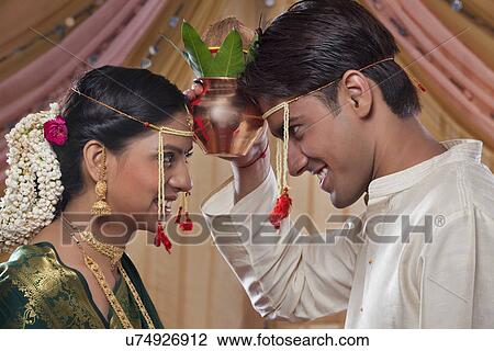 Stock Image - Bride and groom looking at each other while performing rituals . Fotosearch