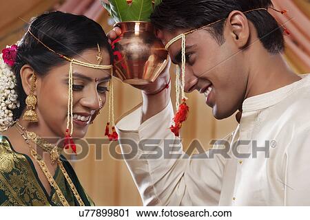 Stock Image - Bride and groom performing Maharashtrian rituals . Fotosearch
