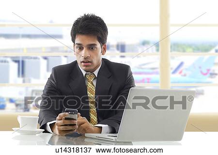 Stock Photo - Businessman getting surprised after reading an sms . Fotosearch
