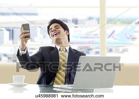 Stock Image - Businessman laughing after reading an sms . Fotosearch