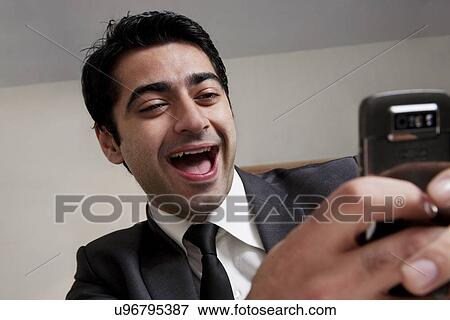 Businessman laughing at an sms on his phone View Large Photo Image Stock Photo - Businessman laughing at an sms on his phone . Fotosearch