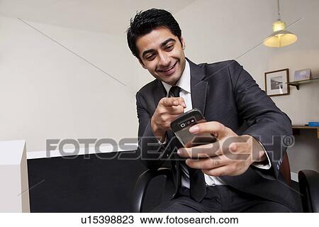 Stock Image - Businessman pointing at his mobile phone . Fotosearch
