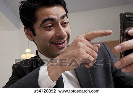 Stock Image - Businessman pointing at his mobile phone . Fotosearch