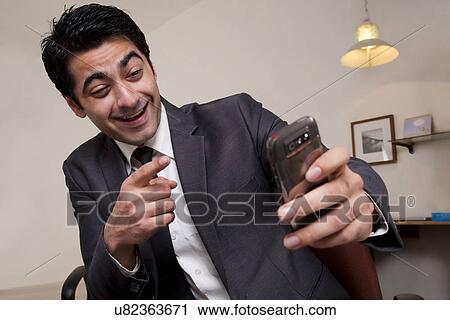 Businessman pointing at his mobile phone View Large Photo Image Stock Image - Businessman pointing at his mobile phone . Fotosearch