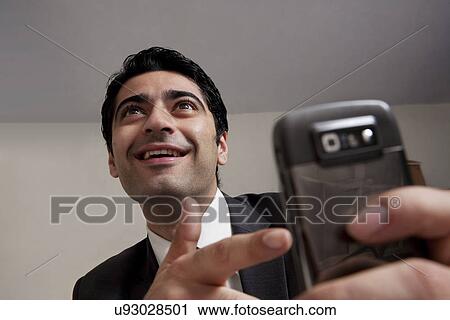 Stock Image - Businessman pointing at his mobile phone . Fotosearch