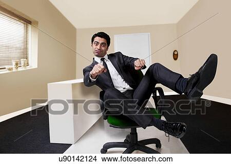 Picture - Businessman pretending to ride a motorbike in the office . Fotosearch