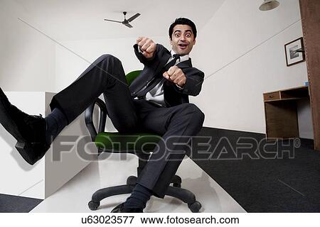 Businessman pretending to ride a motorbike in the office View Large Photo Image Stock Photo - Businessman pretending to ride a motorbike in the office . Fotosearch