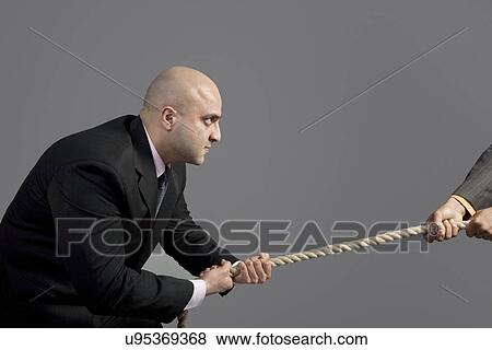 Businessman pulling on a rope View Large Photo Image Stock Photo - Businessman pulling on a rope . Fotosearch