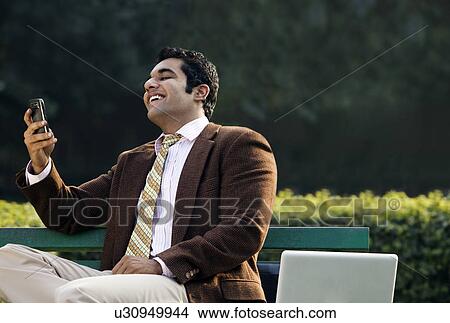 Picture - Businessman reading a message on a mobile phone . Fotosearch