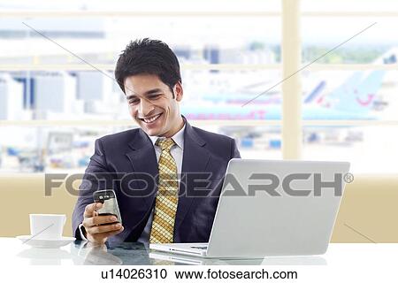 Businessman reading a message on a mobile phone View Large Photo Image Stock Image - Businessman reading a message on a mobile phone . Fotosearch