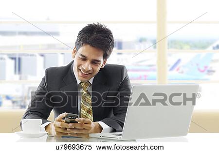 Businessman reading a message on a mobile phone View Large Photo Image Stock Photography - Businessman reading a message on a mobile phone . Fotosearch