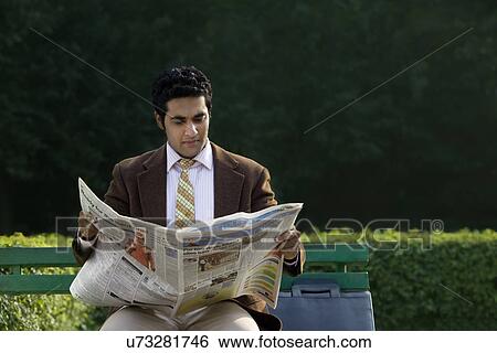 Businessman reading a newspaper in a park View Large Photo Image Stock Photograph - Businessman reading a newspaper in a park . Fotosearch