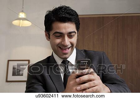 Stock Image - Businessman reading an sms and smiling . Fotosearch