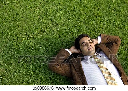 Businessman relaxing on the grass View Large Photo Image Stock Photograph - Businessman relaxing on the grass . Fotosearch