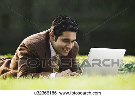 Stock Photograph - Businessman with a laptop in a park . Fotosearch