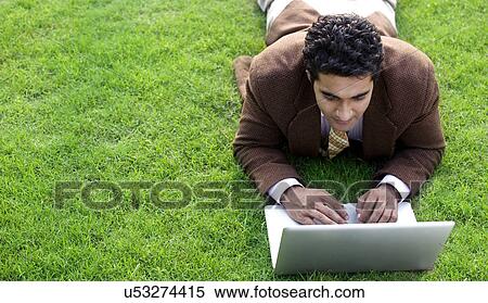 Stock Photography - Businessman working on a laptop in a park . Fotosearch