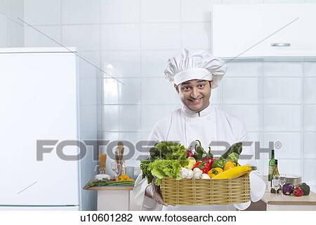 Stock Image - Chef carrying a basket of fresh vegetables . Fotosearch