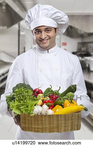 Stock Image - Chef carrying a basket of fresh vegetables . Fotosearch