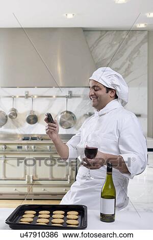Chef reading an sms while holding a glass of wine View Large Photo Image Stock Photograph - Chef reading an sms while holding a glass of wine . Fotosearch