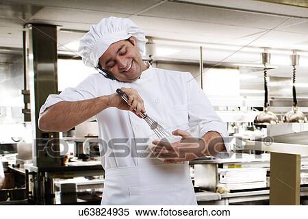 Stock Photography - Chef talking on a mobile phone while beating dough . Fotosearch