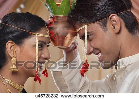 Stock Image - Close-up of young bride and groom performing wedding ceremony together . Fotosearch