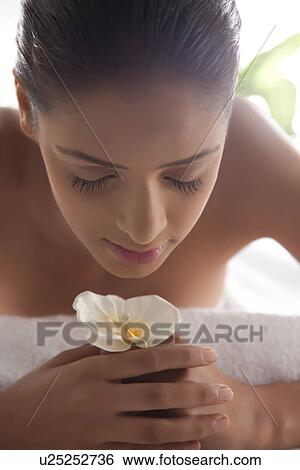 Close-up of young woman holding flower at spa View Large Photo Image Stock Photograph - Close-up of young woman holding flower at spa . Fotosearch