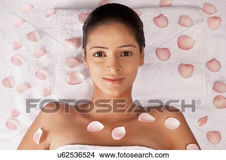 Picture - Close-up portrait of woman lying on massage table with petals . Fotosearch