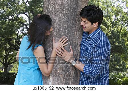 Couple being romantic next to a tree View Large Photo Image Stock Image - Couple being romantic next to a tree . Fotosearch