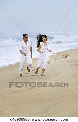 Couple enjoying themselves at a beach View Large Photo Image Stock Photograph - Couple enjoying themselves at a beach . Fotosearch