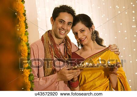 Couple holding a tray of diyas View Large Photo Image Stock Image - Couple holding a tray of diyas . Fotosearch