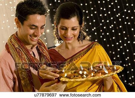 Stock Photo - Couple holding a tray of diyas . Fotosearch
