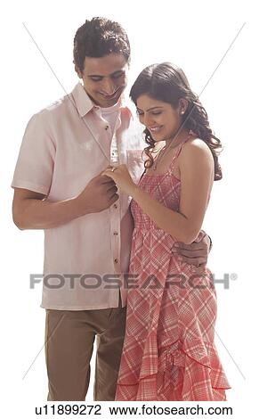 Stock Image - Couple holding each other while looking at ring. Fotosearch