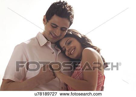 Stock Photo - Couple holding each other while looking at ring. Fotosearch