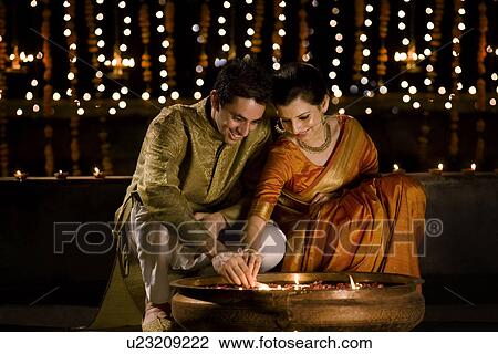 Couple lighting diyas View Large Photo Image Stock Image - Couple lighting diyas . Fotosearch