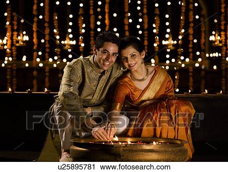 Stock Image - Couple lighting diyas . Fotosearch