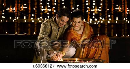 Stock Photo - Couple lighting diyas . Fotosearch