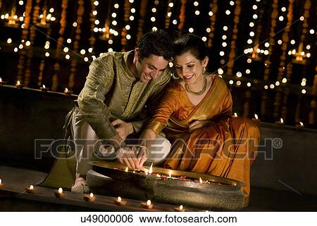 Stock Photograph - Couple lighting diyas . Fotosearch