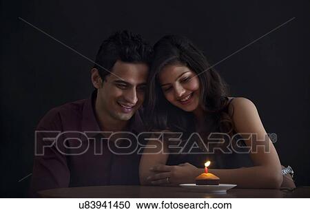 Couple looking at a muffin with a candle View Large Photo Image Stock Image - Couple looking at a muffin with a candle. Fotosearch
