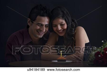 Stock Photo - Couple looking at a muffin with a candle. Fotosearch