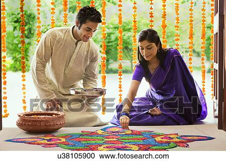 Stock Image - Couple making a rangoli . Fotosearch