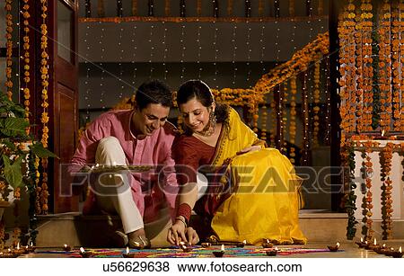 Couple placing diyas View Large Photo Image Stock Photo - Couple placing diyas . Fotosearch