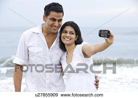 Stock Photo - Couple taking a self portrait at a beach . Fotosearch