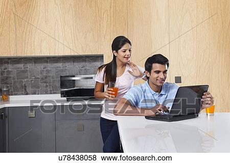 Couple using laptop in kitchen View Large Photo Image Stock Photo - Couple using laptop in kitchen. Fotosearch