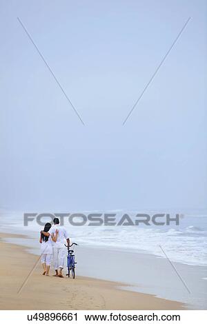 Couple walking on a beach with a bicycle View Large Photo Image Stock Image - Couple walking on a beach with a bicycle . Fotosearch