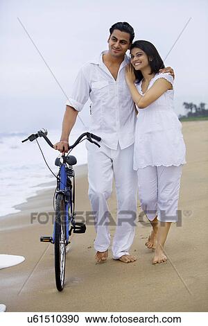 Couple walking on a beach with a bicycle View Large Photo Image Stock Image - Couple walking on a beach with a bicycle . Fotosearch
