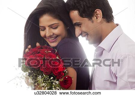 Couple with a bouquet of roses smiling View Large Photo Image Stock Photo - Couple with a bouquet of roses smiling. Fotosearch
