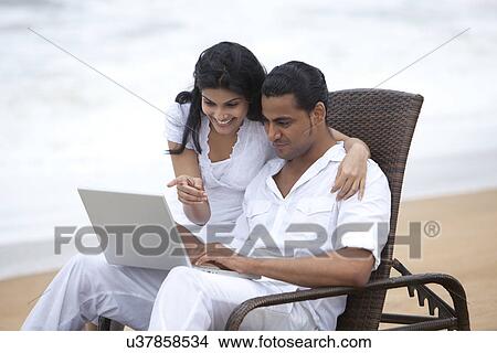 Picture - Couple with a laptop at a beach . Fotosearch