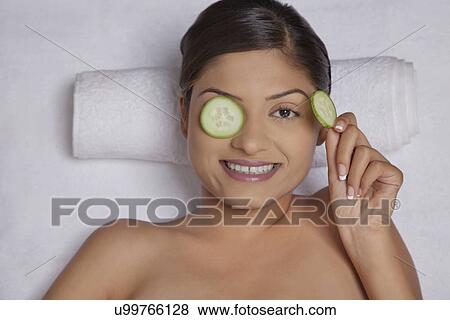 Stock Photo - Cucumber slices on a woman's eyes . Fotosearch