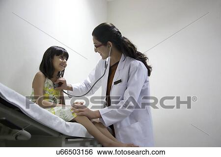 Doctor checking a girl's heartbeat View Large Photo Image Stock Photograph - Doctor checking a girl's heartbeat . Fotosearch