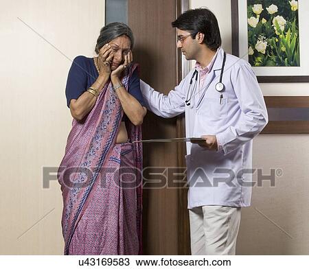 Stock Image - Doctor consoling an old woman . Fotosearch